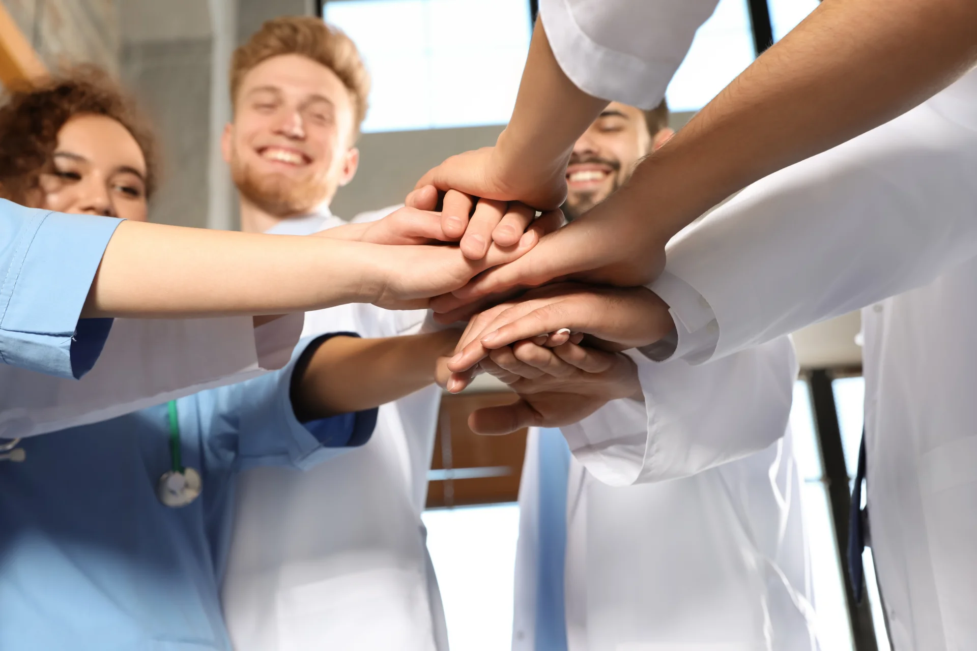 smiling medical staff stack hands in support 2026 03 19 16 56 44 utc